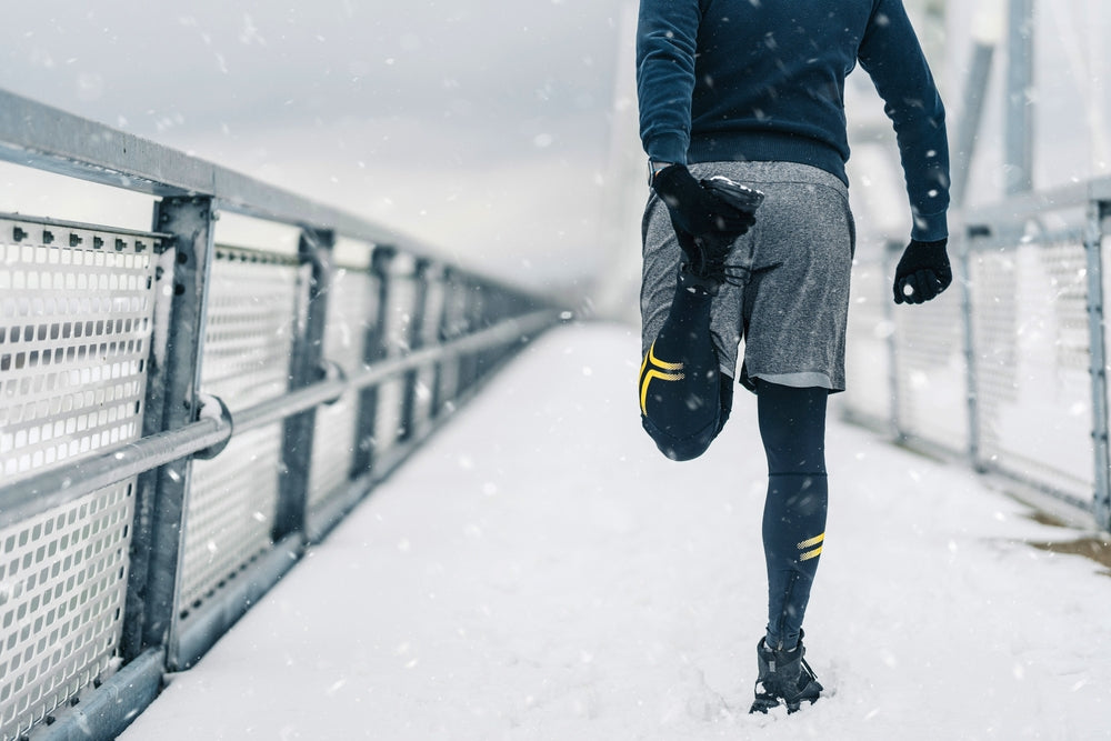 a man preparing to run in winter/snowy weather conditions wearing traction solutions in his shoes made by Grip Studs