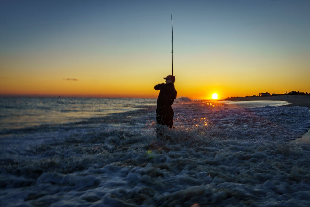 A fisherman wading into the ocean wearing surf fishing boots with studs.